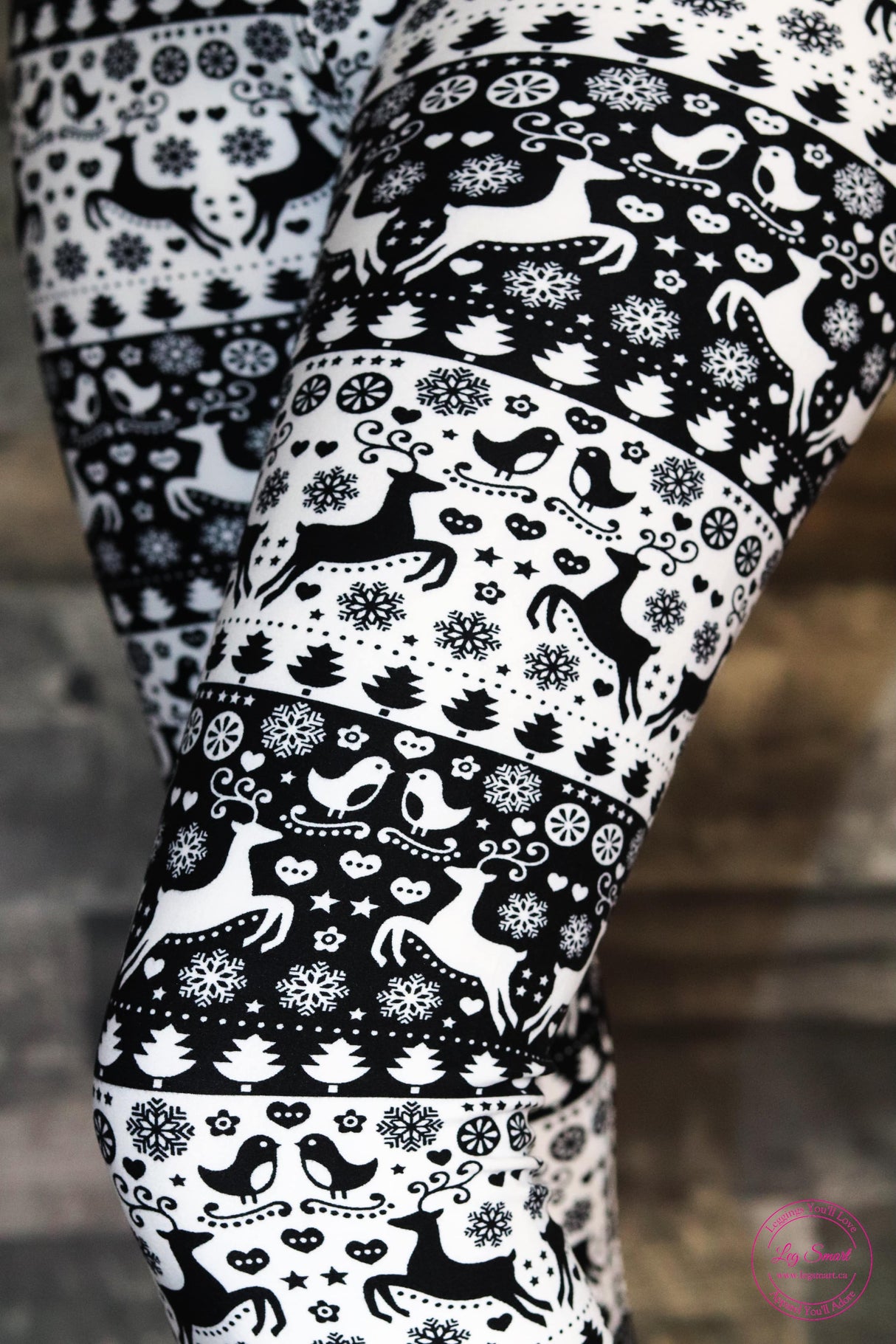 black and white leggings with a festive, wintery pattern of birds, reindeer, snowflakes, and trees.
