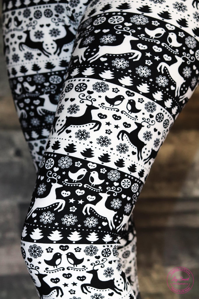 black and white leggings with a festive, wintery pattern of birds, reindeer, snowflakes, and trees. 